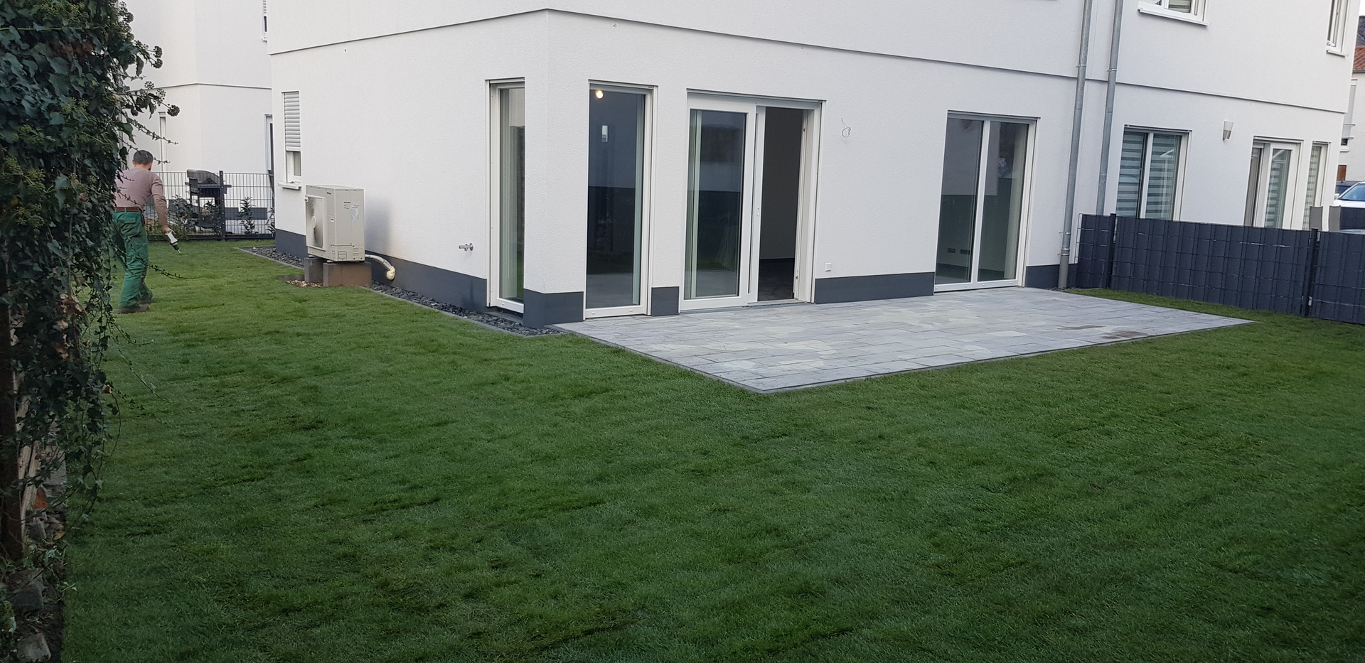 Fertig angelegter Garten mit Natursteinterrasse und frischem Rollrasen
