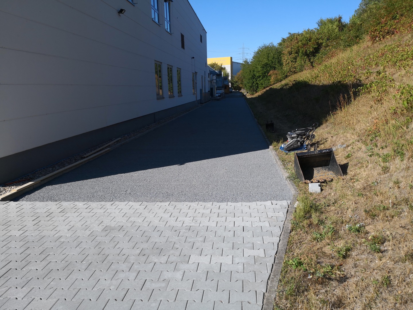 Frisch verlegter Pflasterweg mit Rasengittersteinen entlang einer Halle